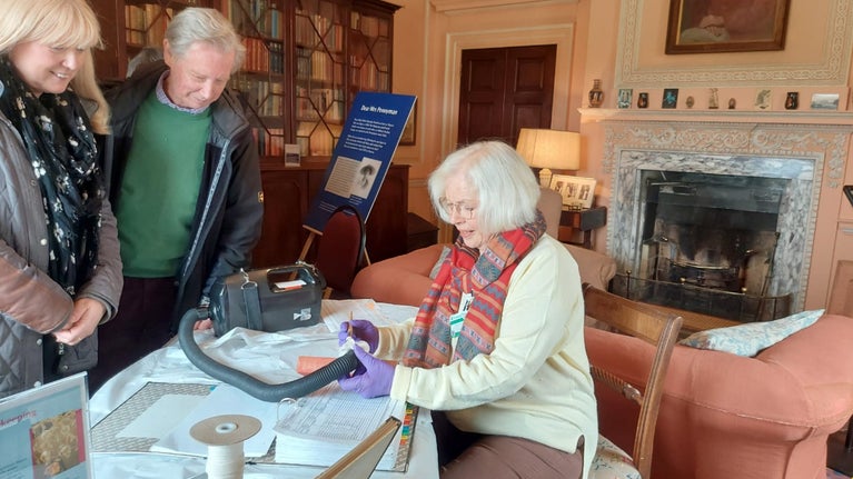Volunteer cleaning collections in front of visitors